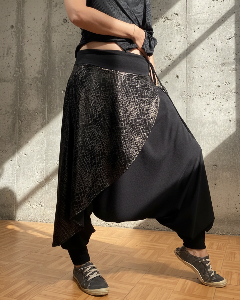 Person wearing a black outfit with a textured pattern against a concrete wall.