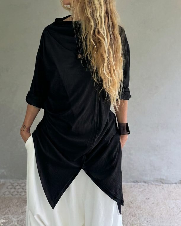woman in black glorka jedi top and white pants in front of the concrete wall