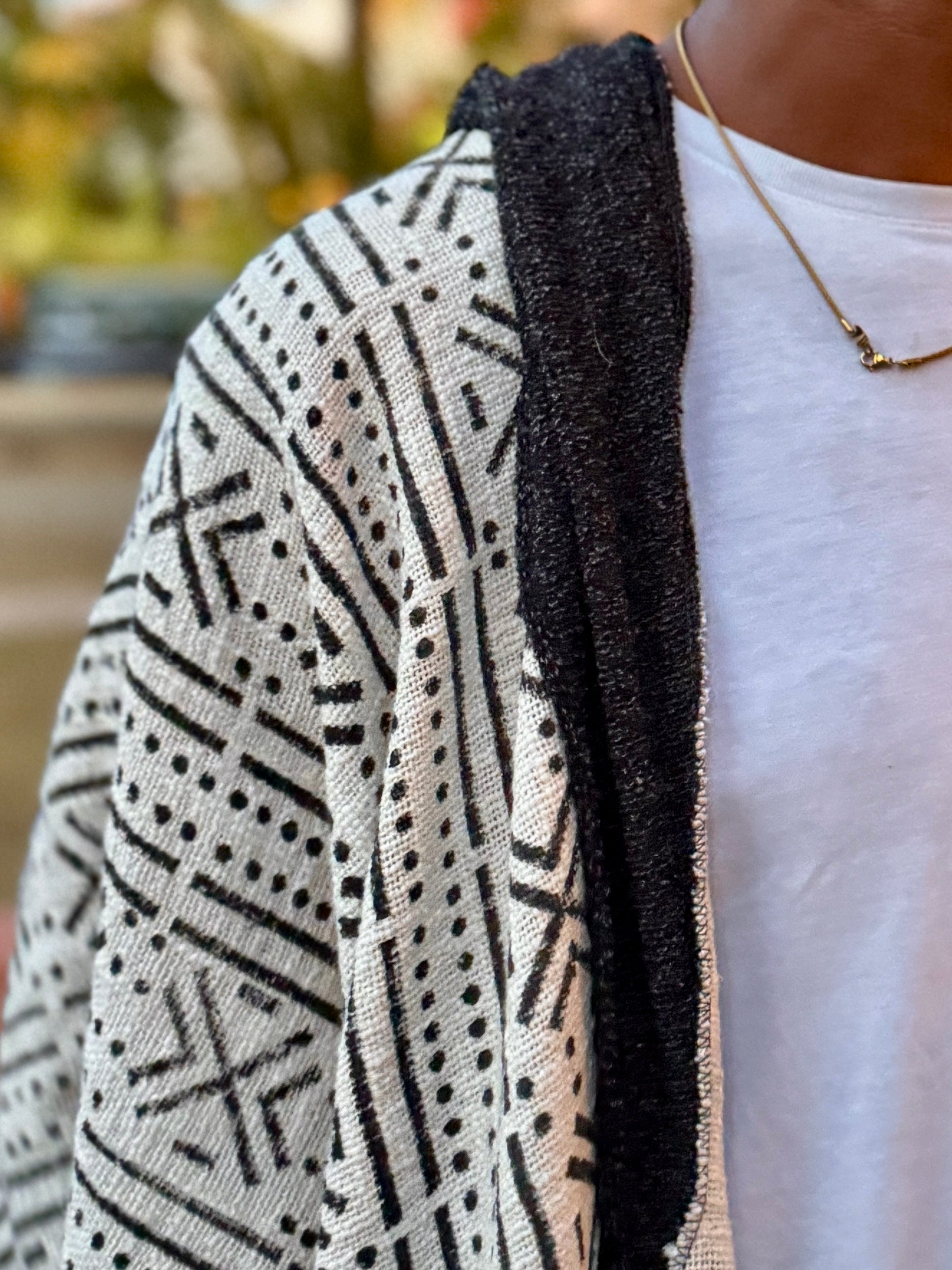 Person wearing a patterned cardigan with a blurred outdoor background