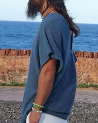 Man standing by the ocean with a brick wall and blue sky in the background