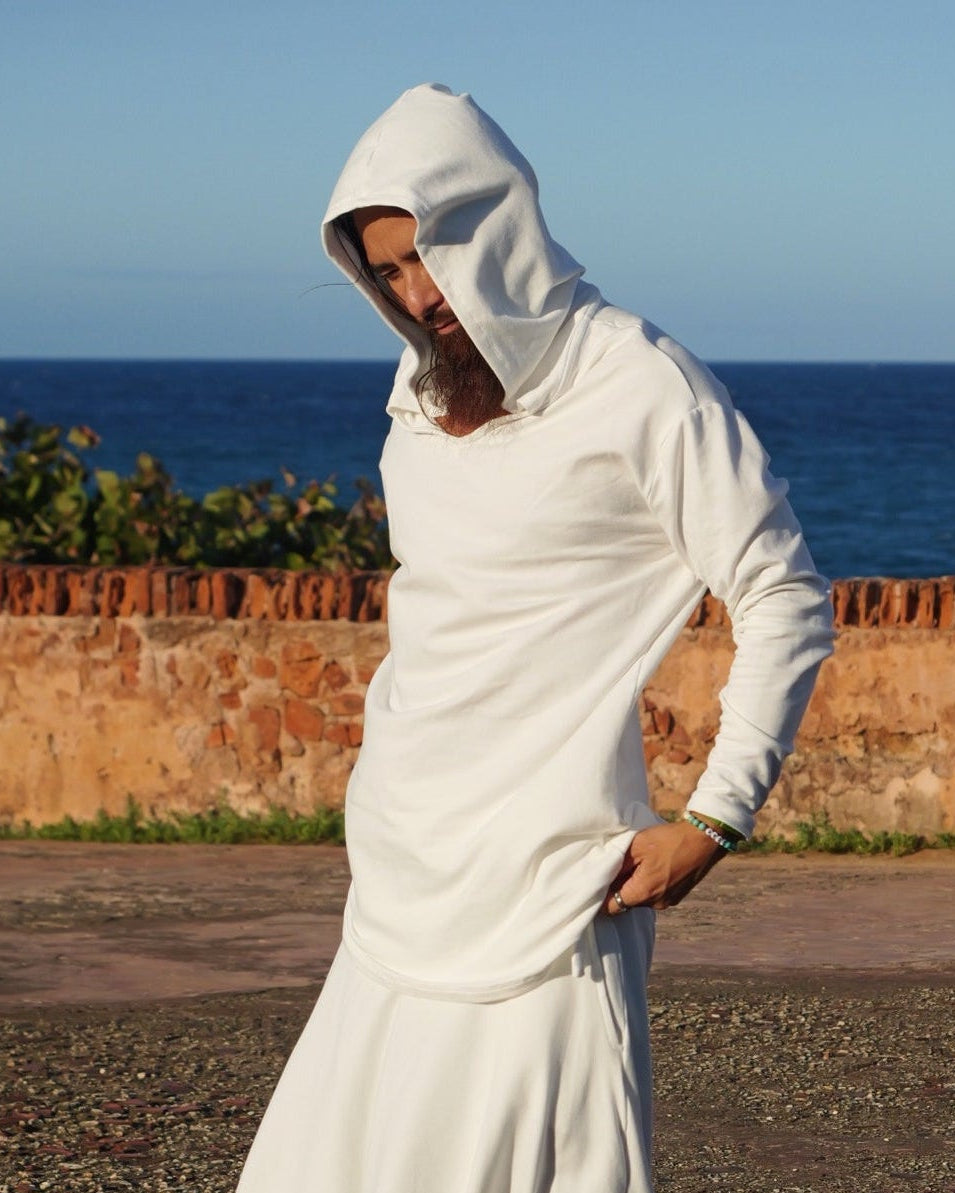 Person in a white outfit standing on a textured surface with a clear blue sky.