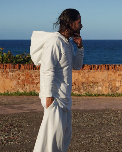 Person in white outfit standing on a road with a blue sky background