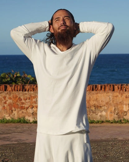 Person in a white dress standing on a road with a blue wall and greenery in the background