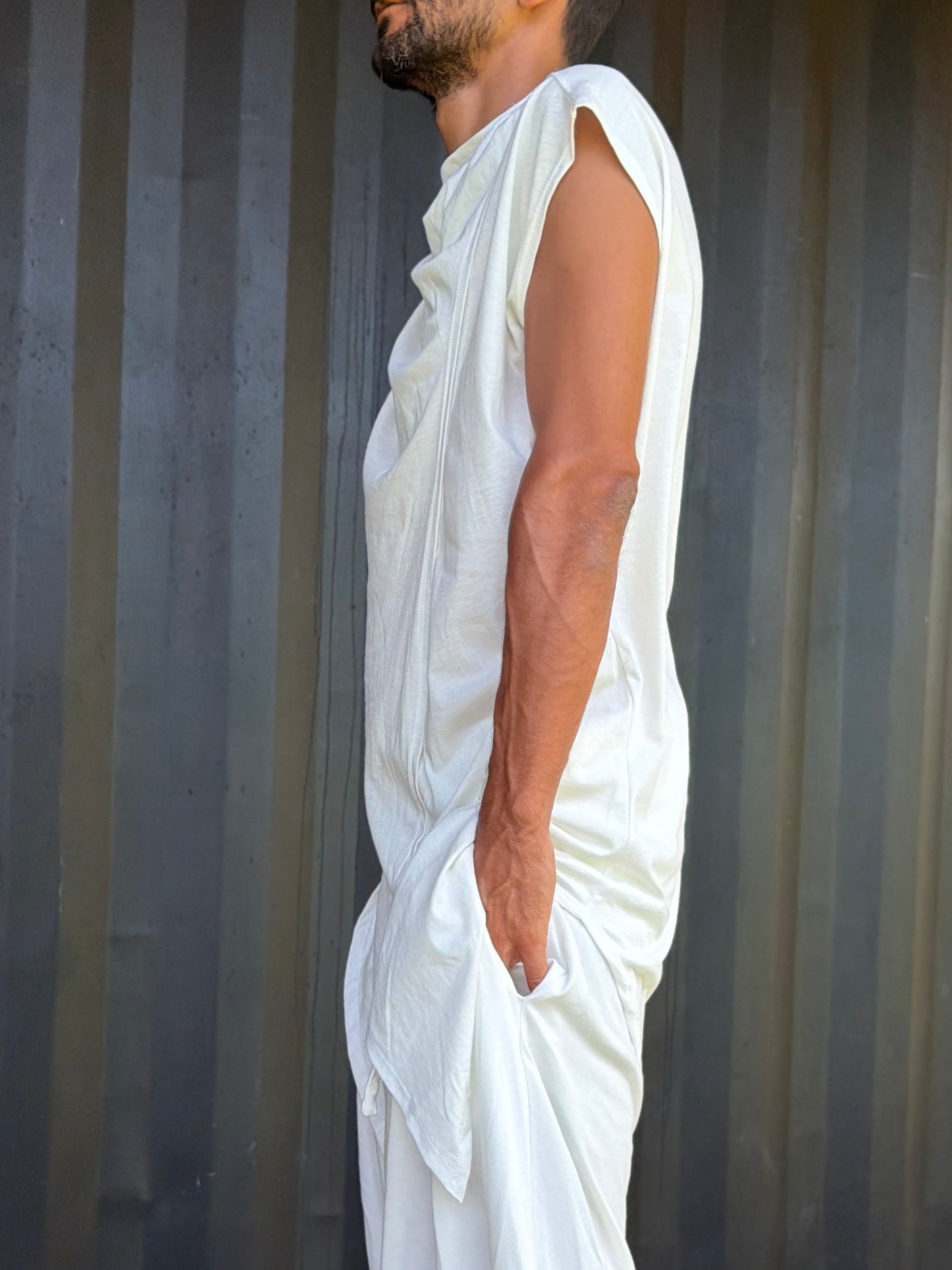 Person wearing a white organic cotton glorka outfit against a corrugated metal background