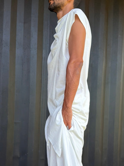 Person wearing a white organic cotton glorka outfit against a corrugated metal background