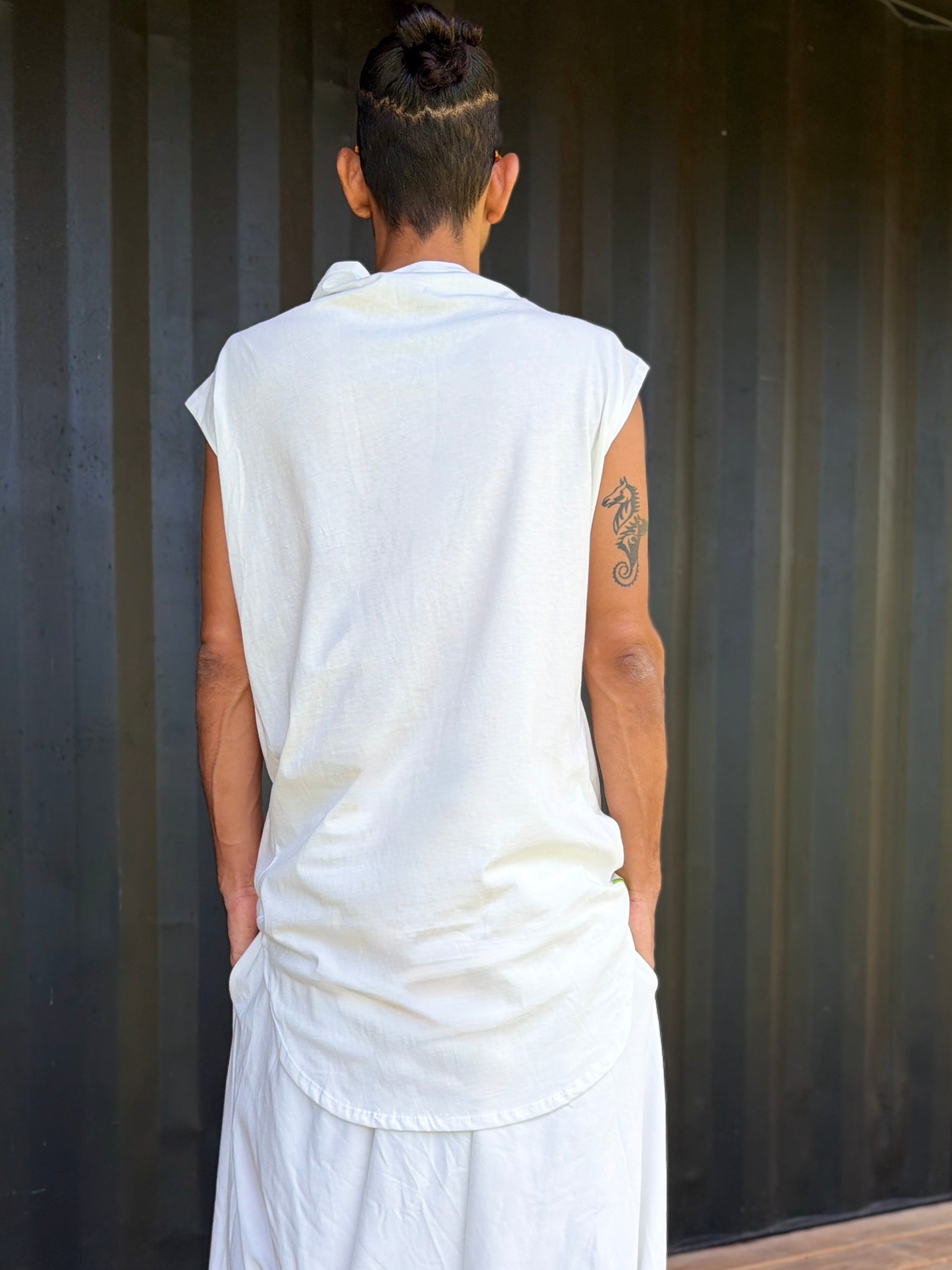 Person wearing a white organic cotton glorka jedi top outfit against a corrugated metal background