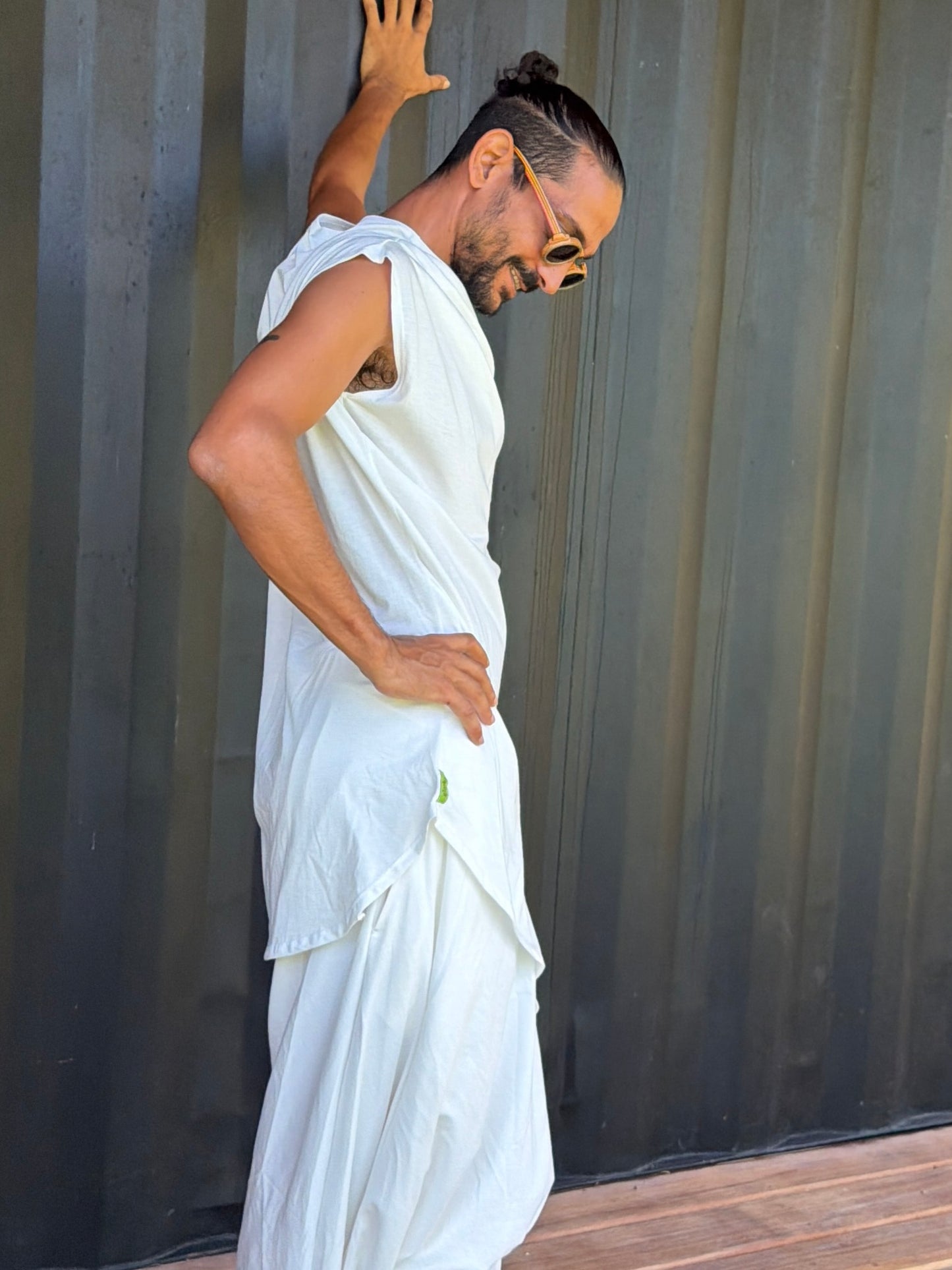 Person wearing a white organic cotton glorka outfit against a corrugated metal background